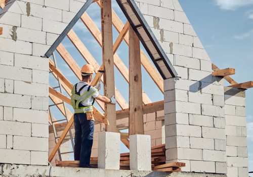 Concentrated man in safety gear building a house